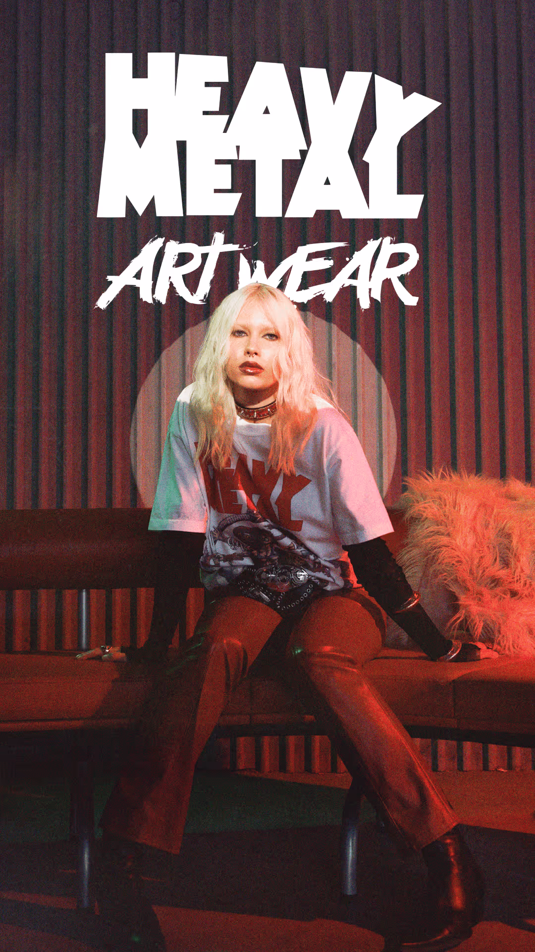 Young woman with platinum blonde hair wearing a white graphic heavy metal art wear t-shirt, red leather pants, black boots, and sitting on a bench with a fuzzy orange pillow.