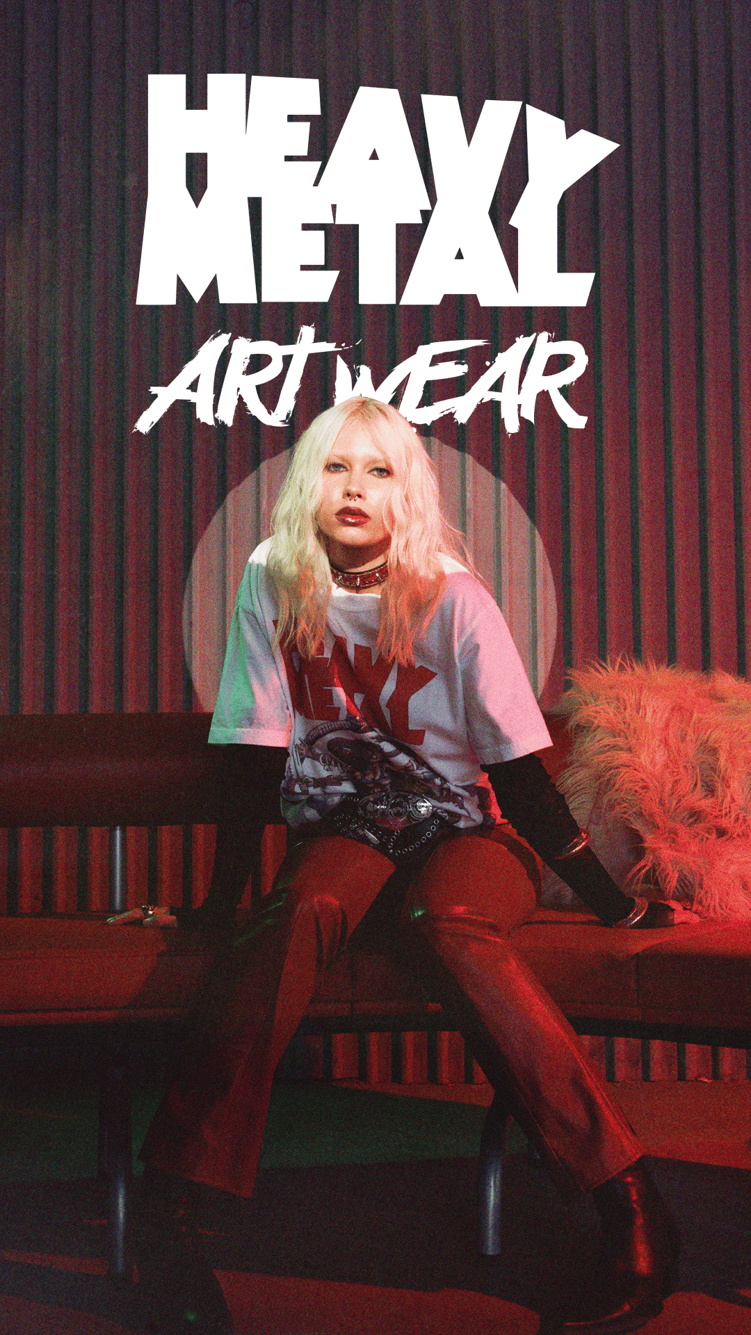 Young woman with platinum blonde hair wearing a white graphic heavy metal art wear t-shirt, red leather pants, black boots, and sitting on a bench with a fuzzy orange pillow.