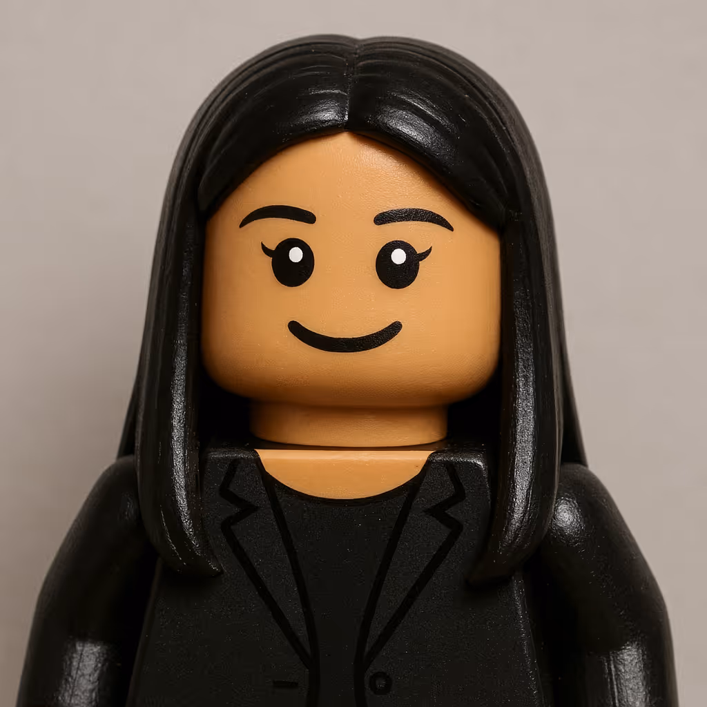 Lego minifigure with long black hair, black blazer, and smiling face on a gray background.