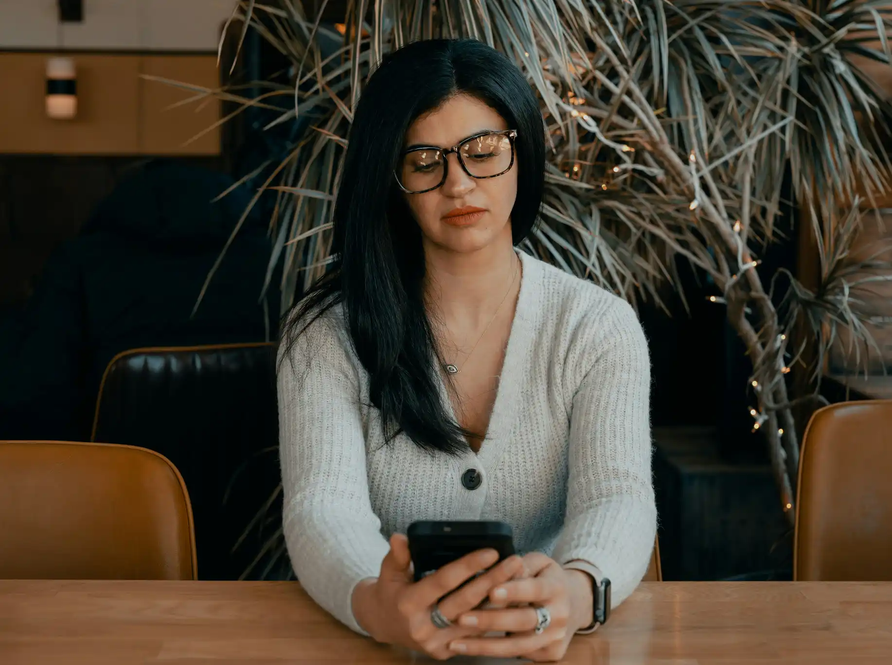 Woman sitting at desk, looking down at phone