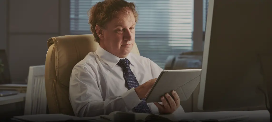 Business professional reviewing analytics on a tablet at his desk