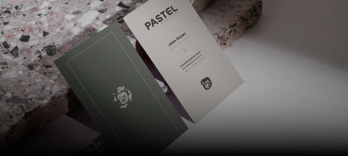 Pastel Creative business cards displayed on textured stone surfaces.