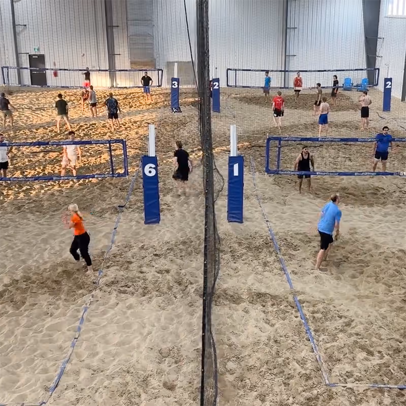 4 beach volleyball courts full of players playing at The Beach Hangar