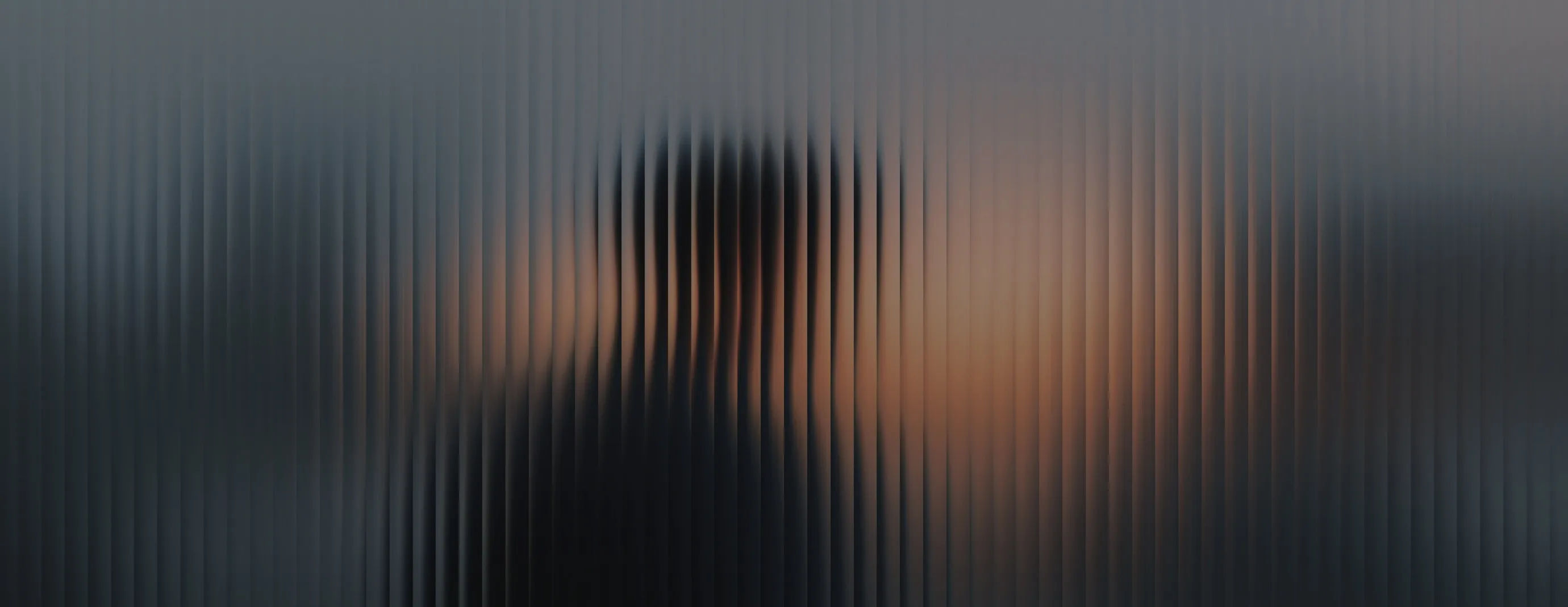 Silhouetted person wearing glasses visible through textured vertical glass panels creating a striped distortion effect.