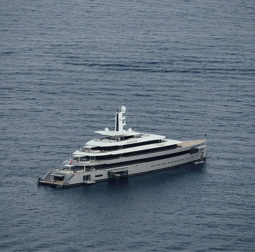 Large modern luxury yacht with multiple decks floating on calm sea water.