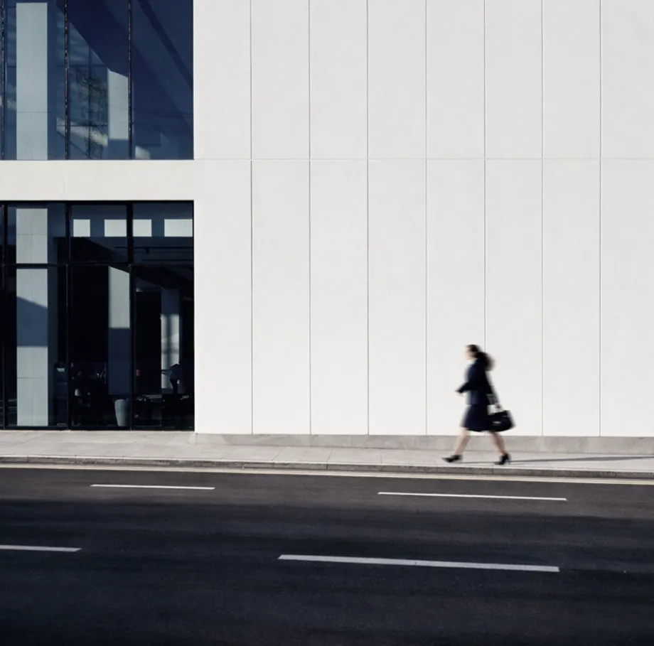 Four people seated around a conference table in a glass-walled office with large windows overlooking a cityscape.