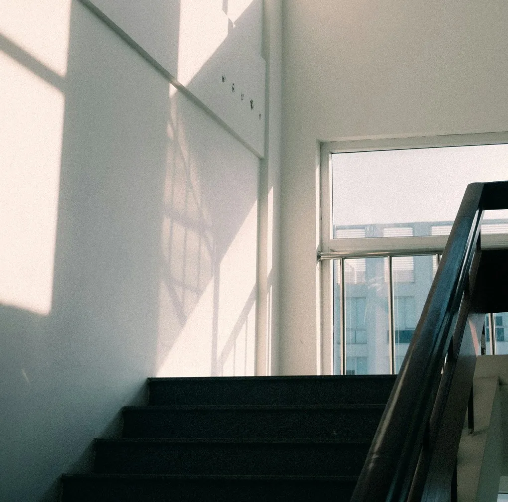 Four people seated around a conference table in a glass-walled office with large windows overlooking a cityscape.