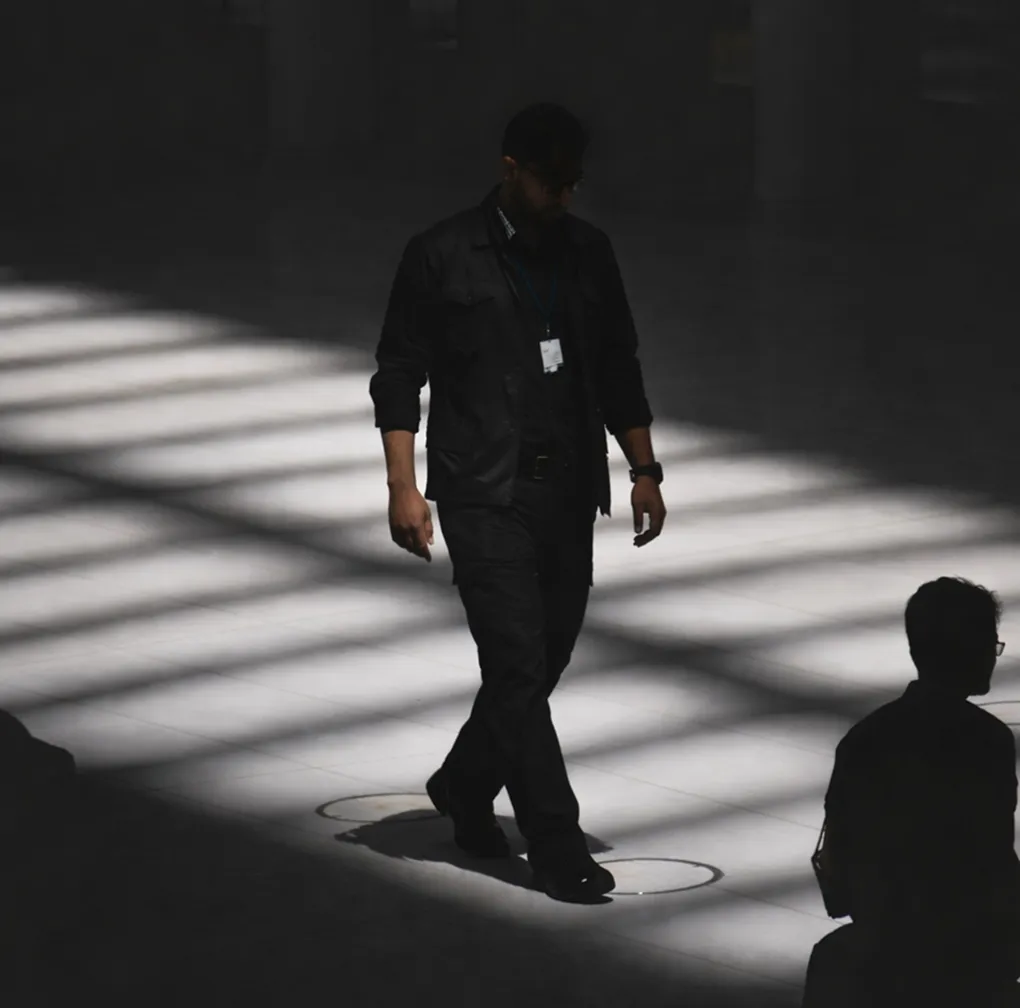 Four people seated around a conference table in a glass-walled office with large windows overlooking a cityscape.
