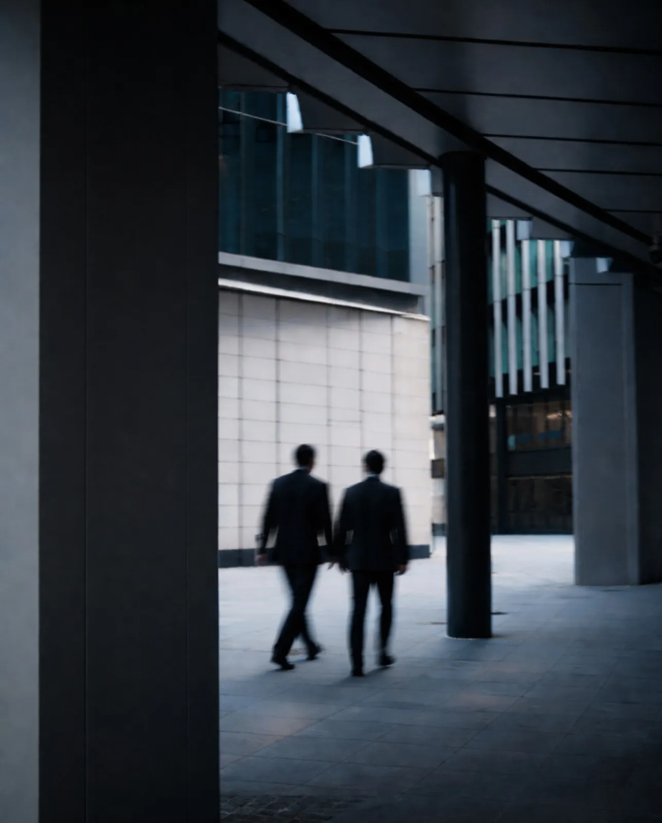 Blurred silhouette of a businessperson walking and talking on a phone beside a tiled urban building.