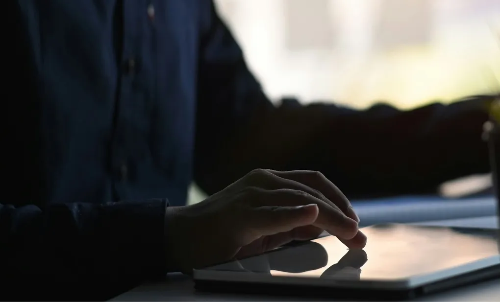 Crowd at a concert with raised hands and bright stage lights illuminating the performers.