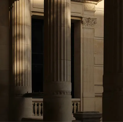Blurred man in a suit walking and talking on a phone outside a modern tiled building.