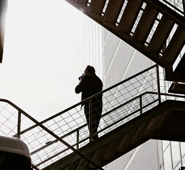 Blurred silhouette of a businessperson walking and talking on a phone beside a tiled urban building.