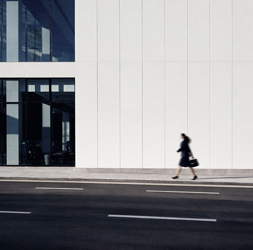 Four people seated around a conference table in a glass-walled office with large windows overlooking a cityscape.