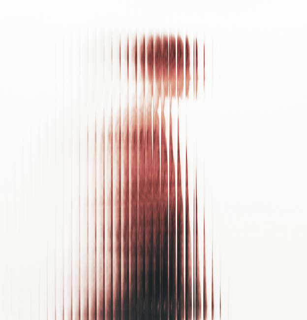 Blurred silhouette of a businessperson walking and talking on a phone beside a tiled urban building.