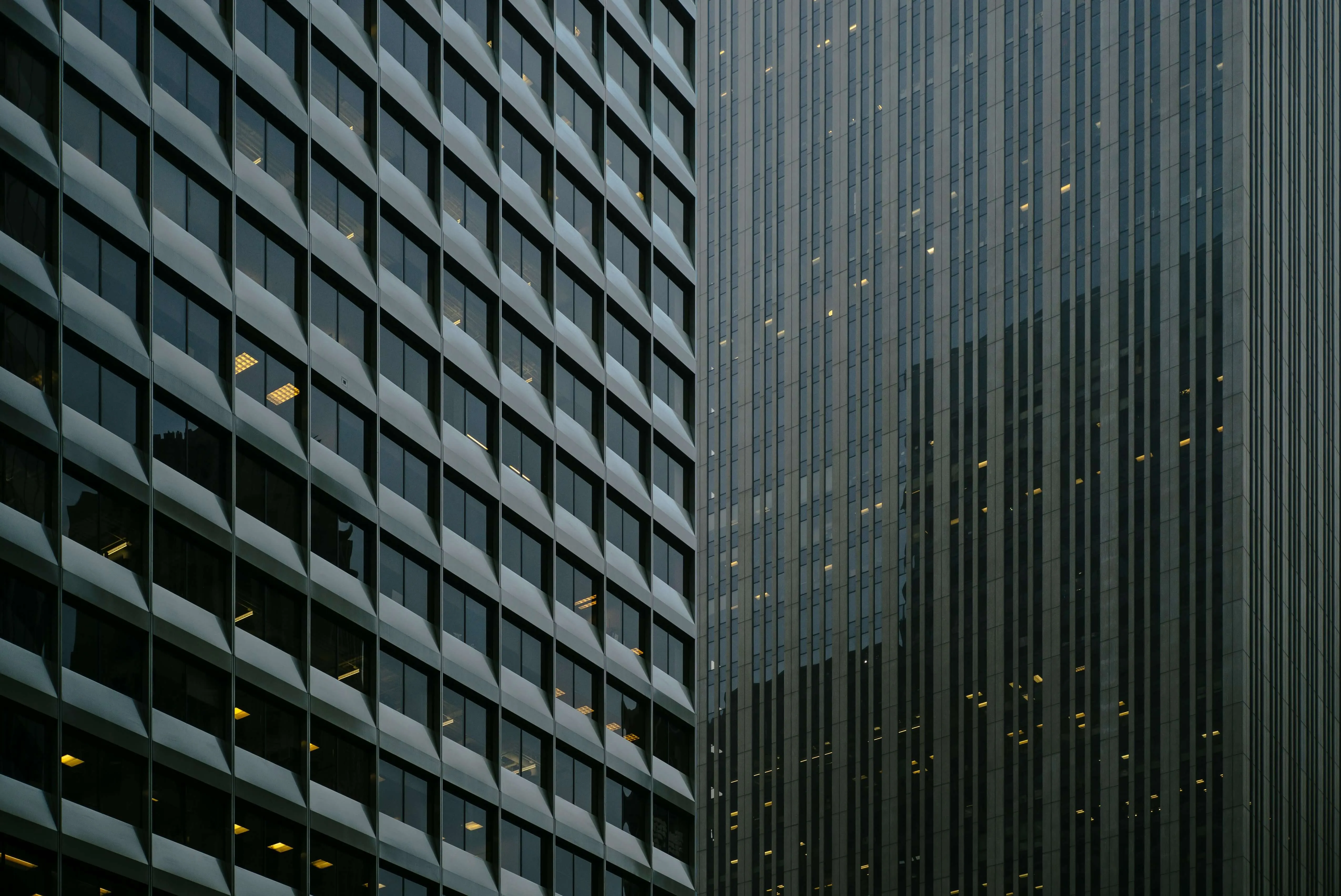 Four people seated around a conference table in a glass-walled office with large windows overlooking a cityscape.