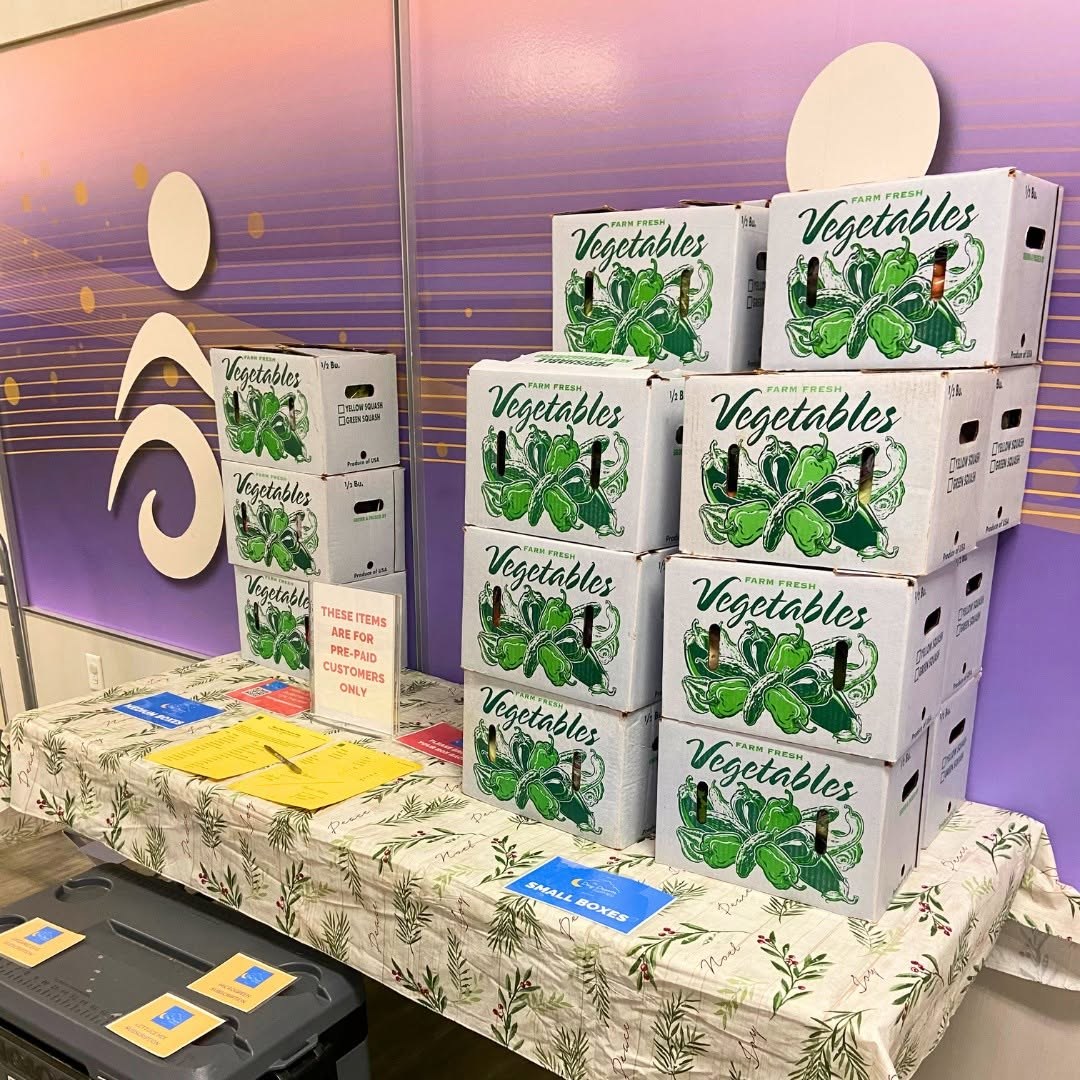 Boxes staged at a Day Dream Farmer pickup site with a small-boxes sign and sign-out sheets on the table