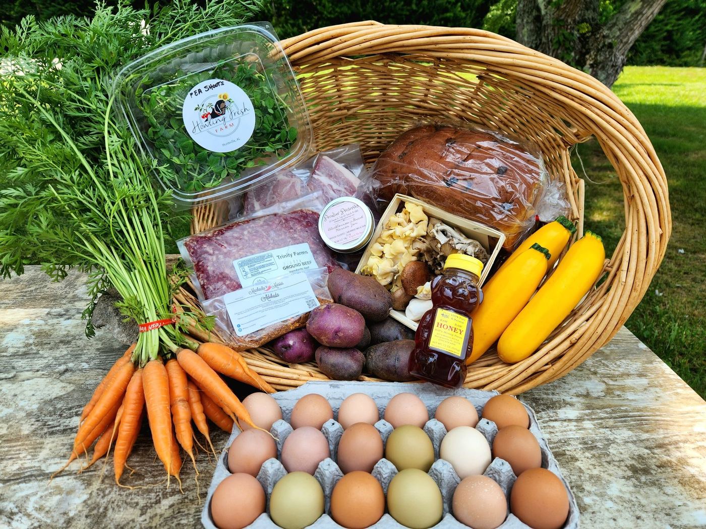 A Howling Fresh share in a basket: carrots, pea shoots, Trinity Farms ground beef, mushrooms, bread, jam, honey, purple potatoes, yellow squash and a flat of eggs