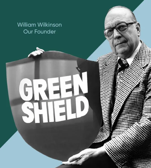 Black-and-white photo of William Wilkinson, founder of Green Shield, holding a large shield with the company name