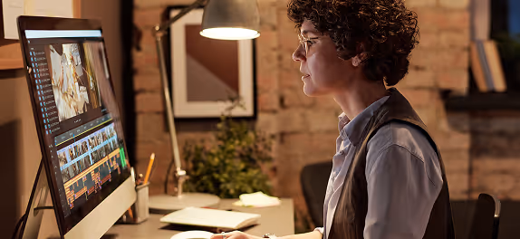 A curly haired woman using an iMac in an apartment.