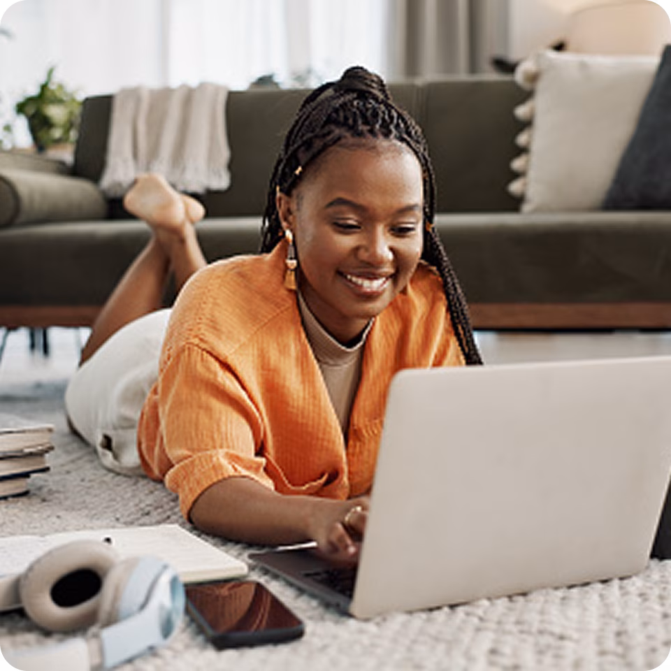 A woman smiling while using a laptop for digital cognitive behavioural therapy, showcasing how a digital mental health support platform provides online mental health therapy in Canada.