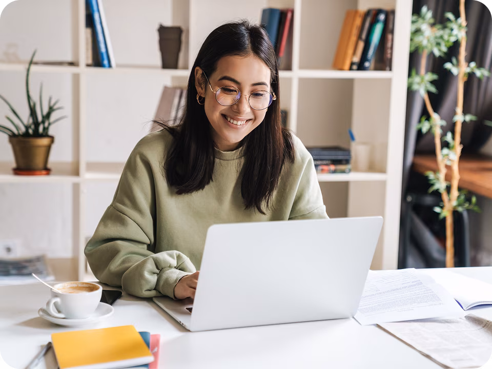 A woman smiling while looking at her laptop, representing the process of matching with a licensed therapist for a virtual therapy session in Canada via a digital mental health support platform.

