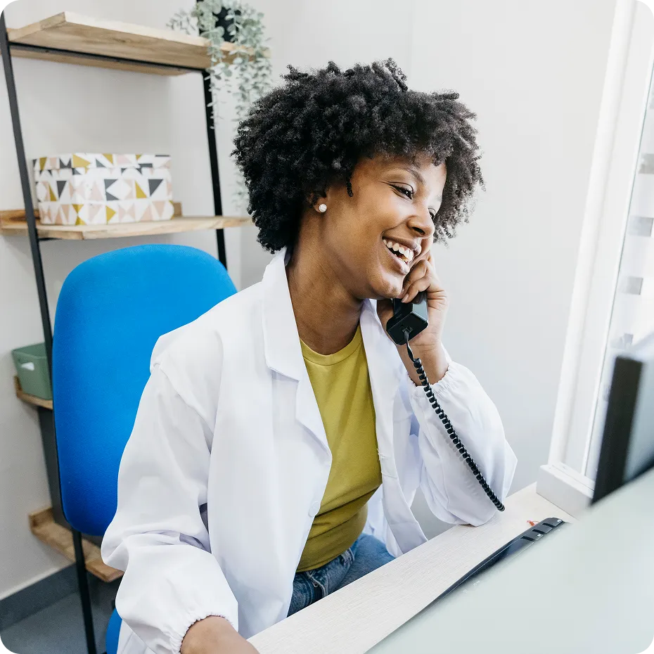 A doctor speaking on a landline phone while using the computer