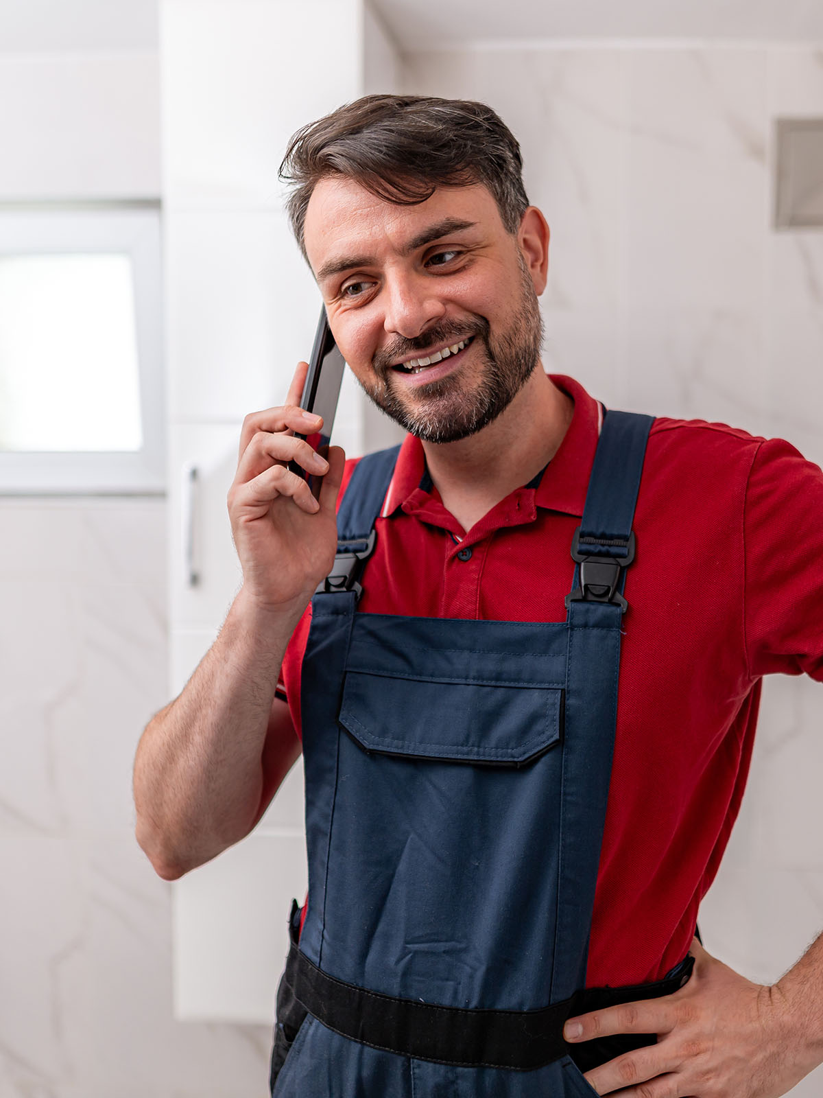 Plumber in work overalls taking a call from a customer