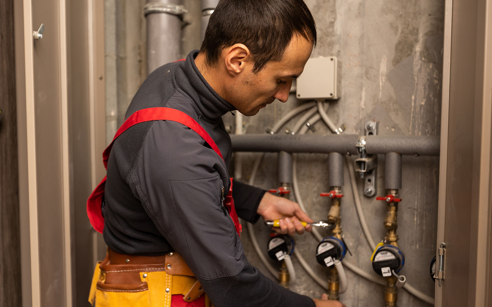 Plumber servicing water lines in a utility room at a home in Oak Ridge, Tennessee