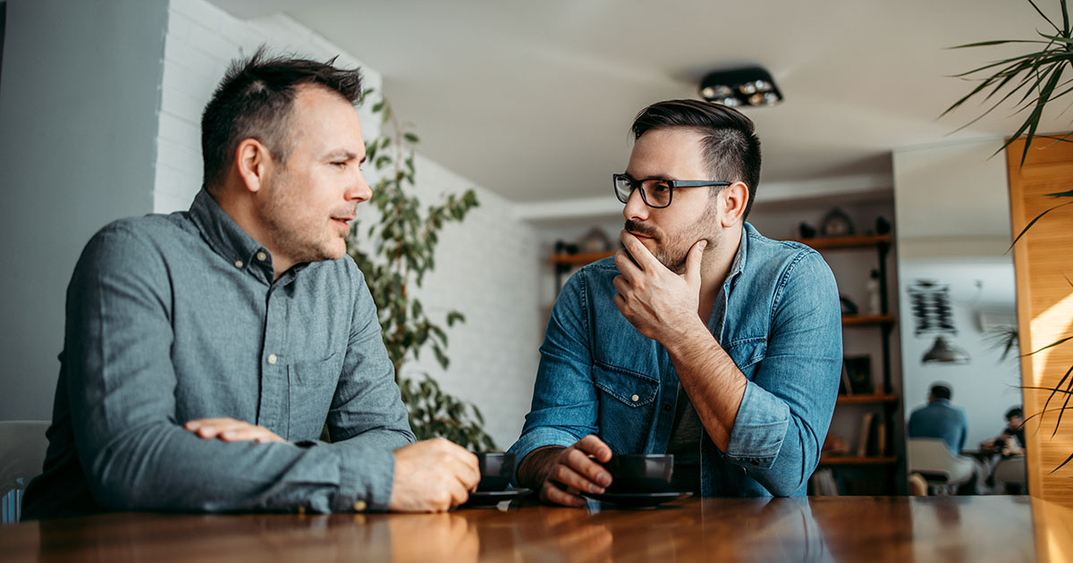 Two contractors talking across a table about hiring a marketing company