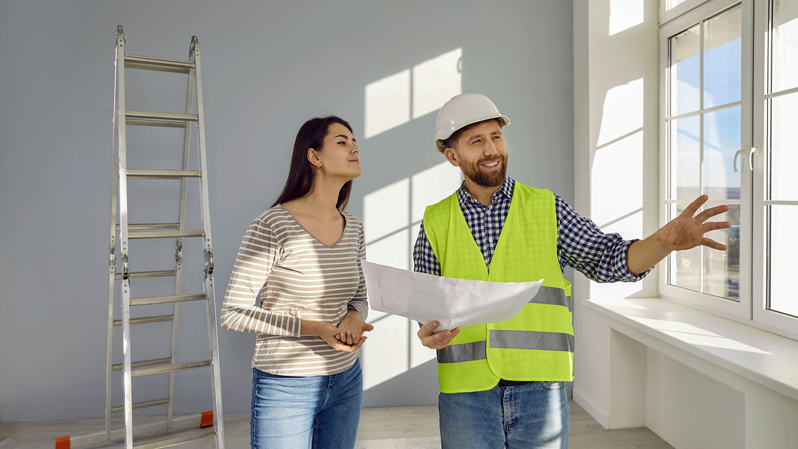 Contractor explaining project plans to a homeowner inside a house under renovation