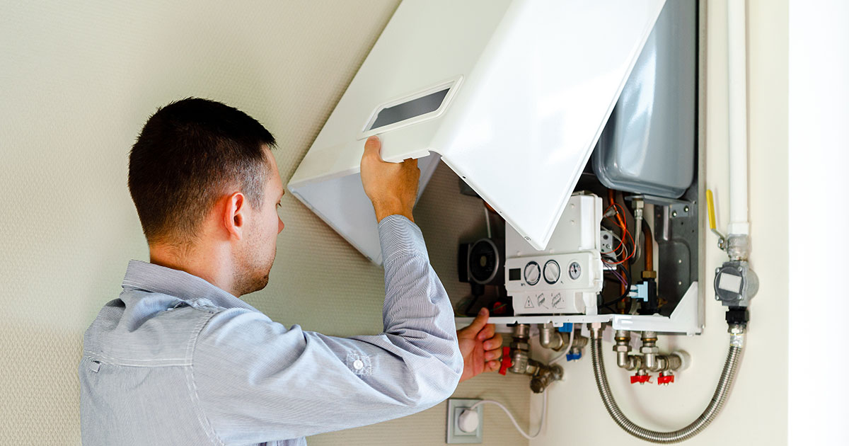Plumber servicing a wall-mounted water heater and supply pipes in a Maryville home