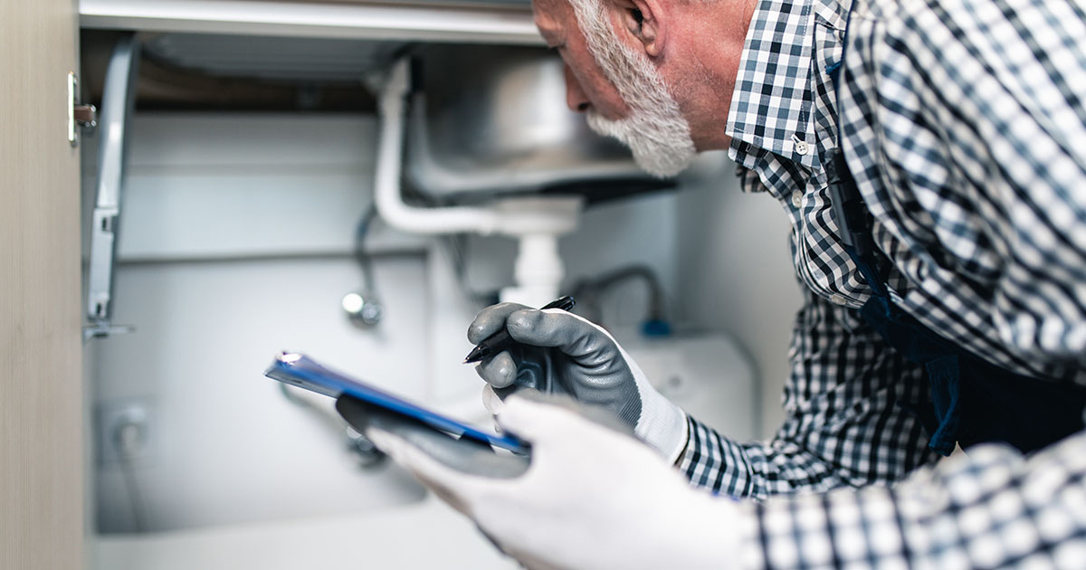 Plumber working with tools under a kitchen sink