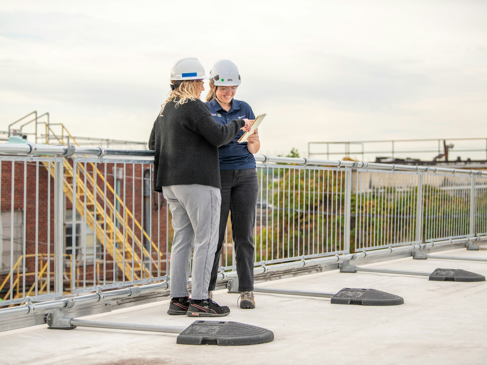Two roofing professionals in hard hats inspecting a commercial flat roof
