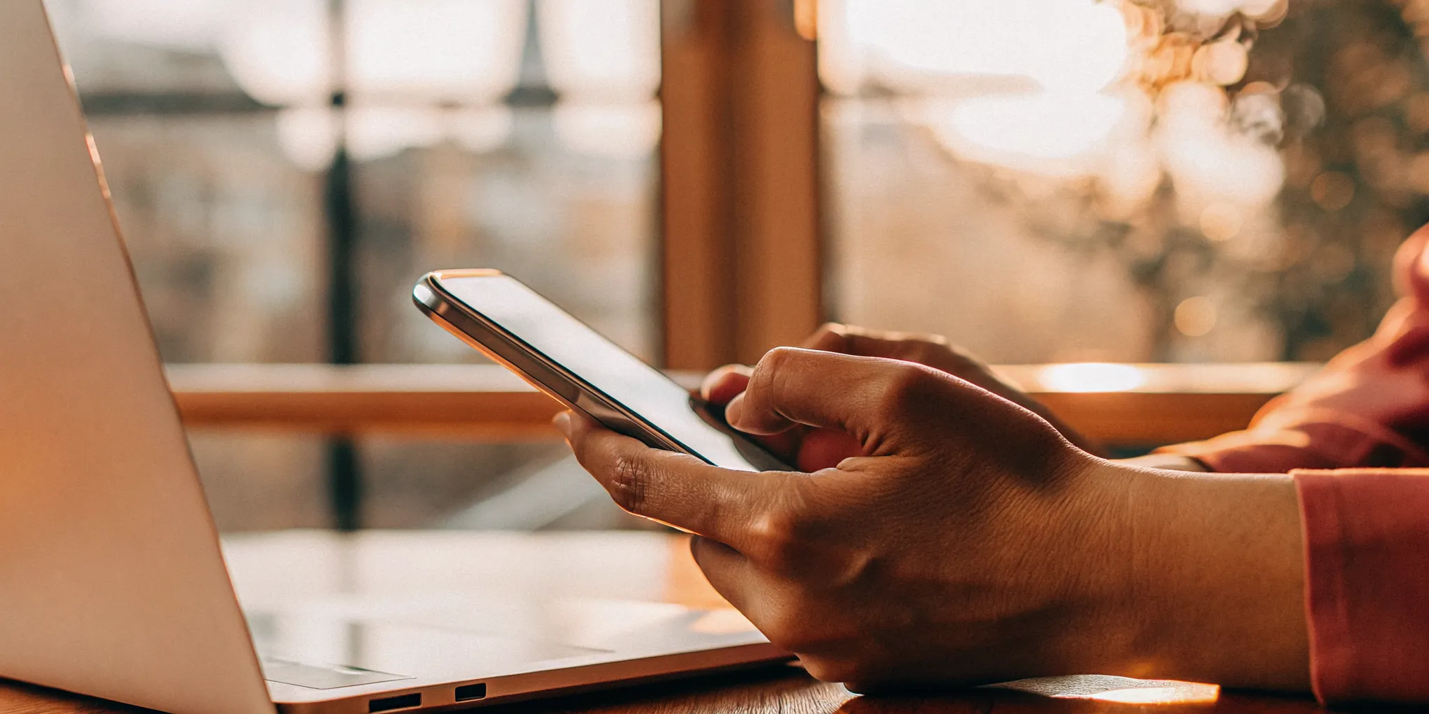 Hands using a smartphone and laptop to manage Canadian financial data portability.