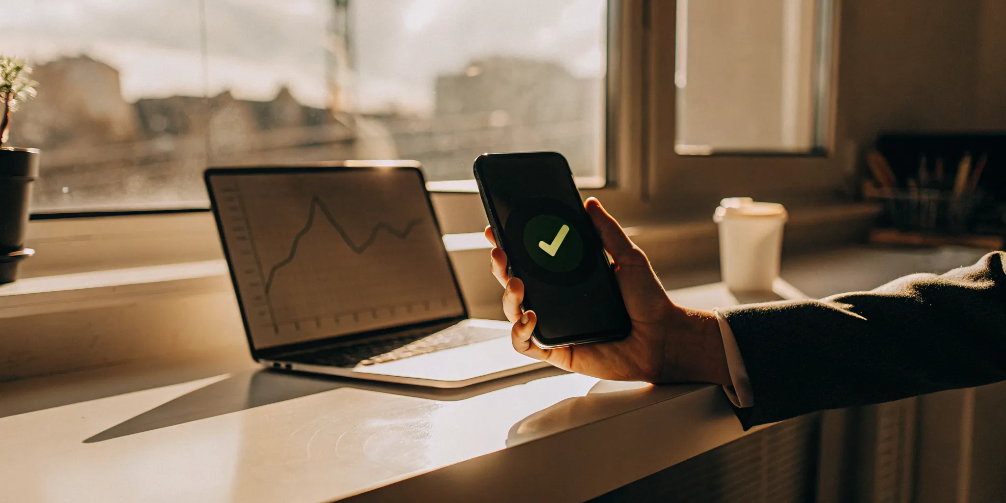 A person gets quick same day loan approval on a smartphone next to a laptop.