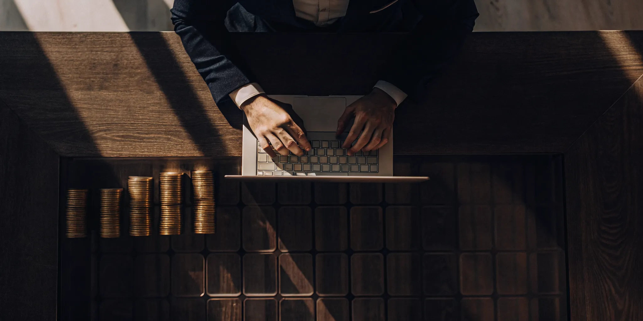 A person researching installment loans on a laptop with stacks of coins on the desk.