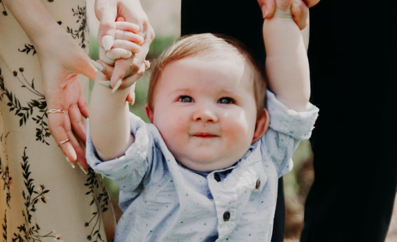 Small boy smiling while being held by his parents.