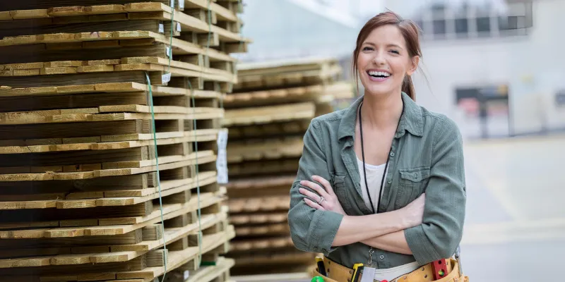 A smiling woman small business owner working in the construction industry standing next to her supplies.