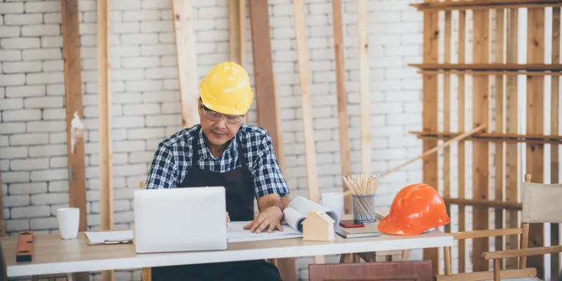 Carpentry business owner reviewing Bizcap survey on documents and laptop