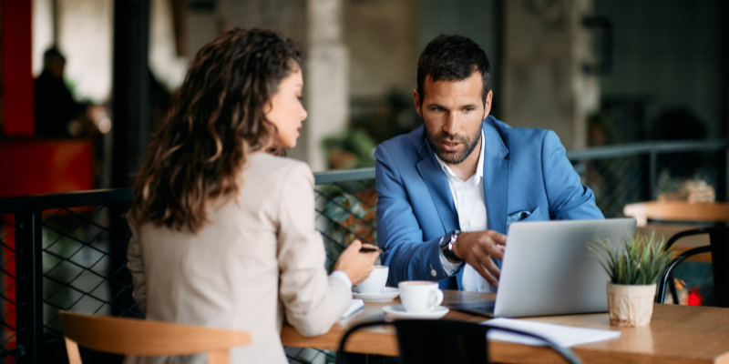 A broker sitting with their client at a café discussing business loan options.