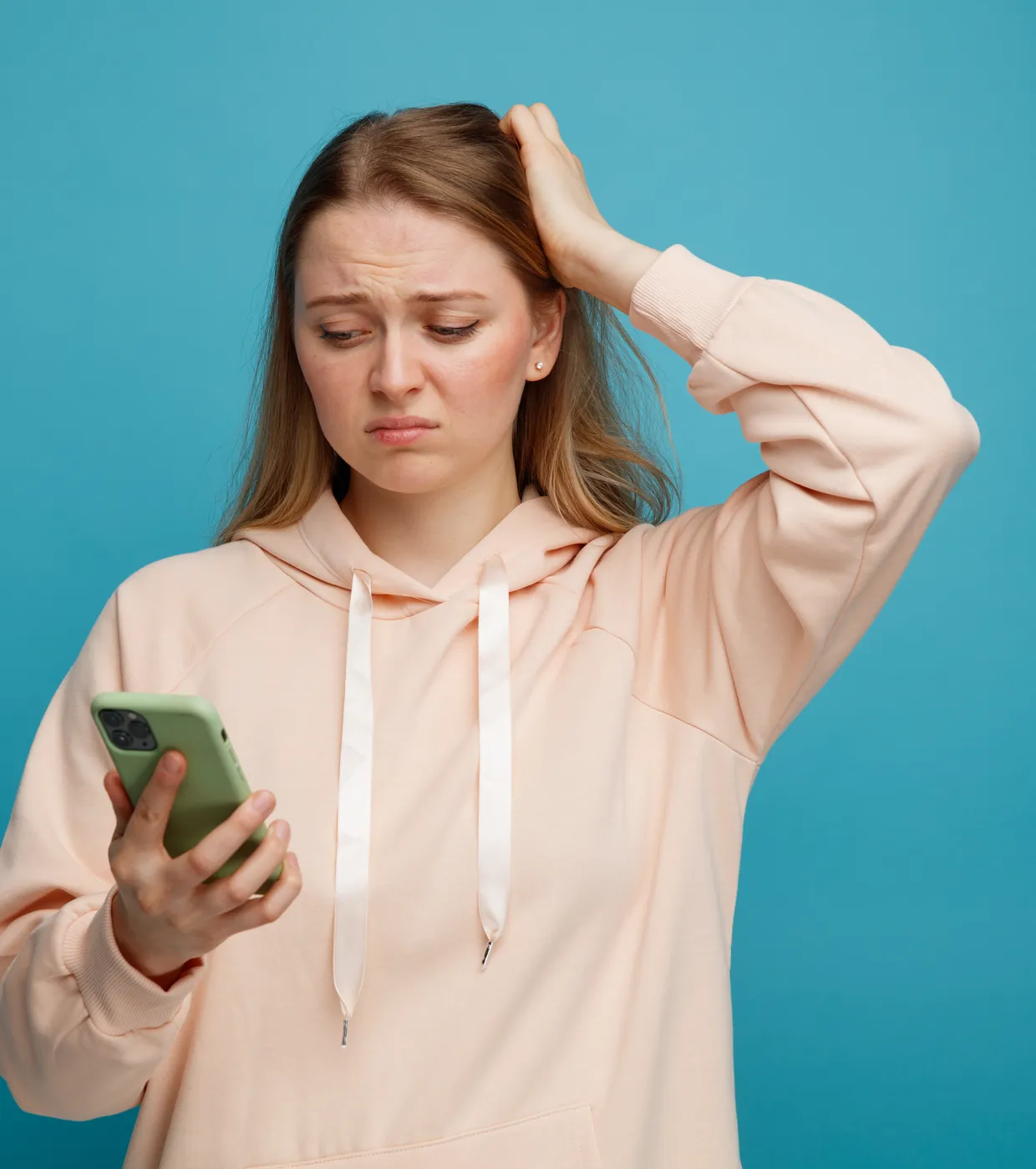Une femme consulte son t&eacute;l&eacute;phone, l'air inquiet.