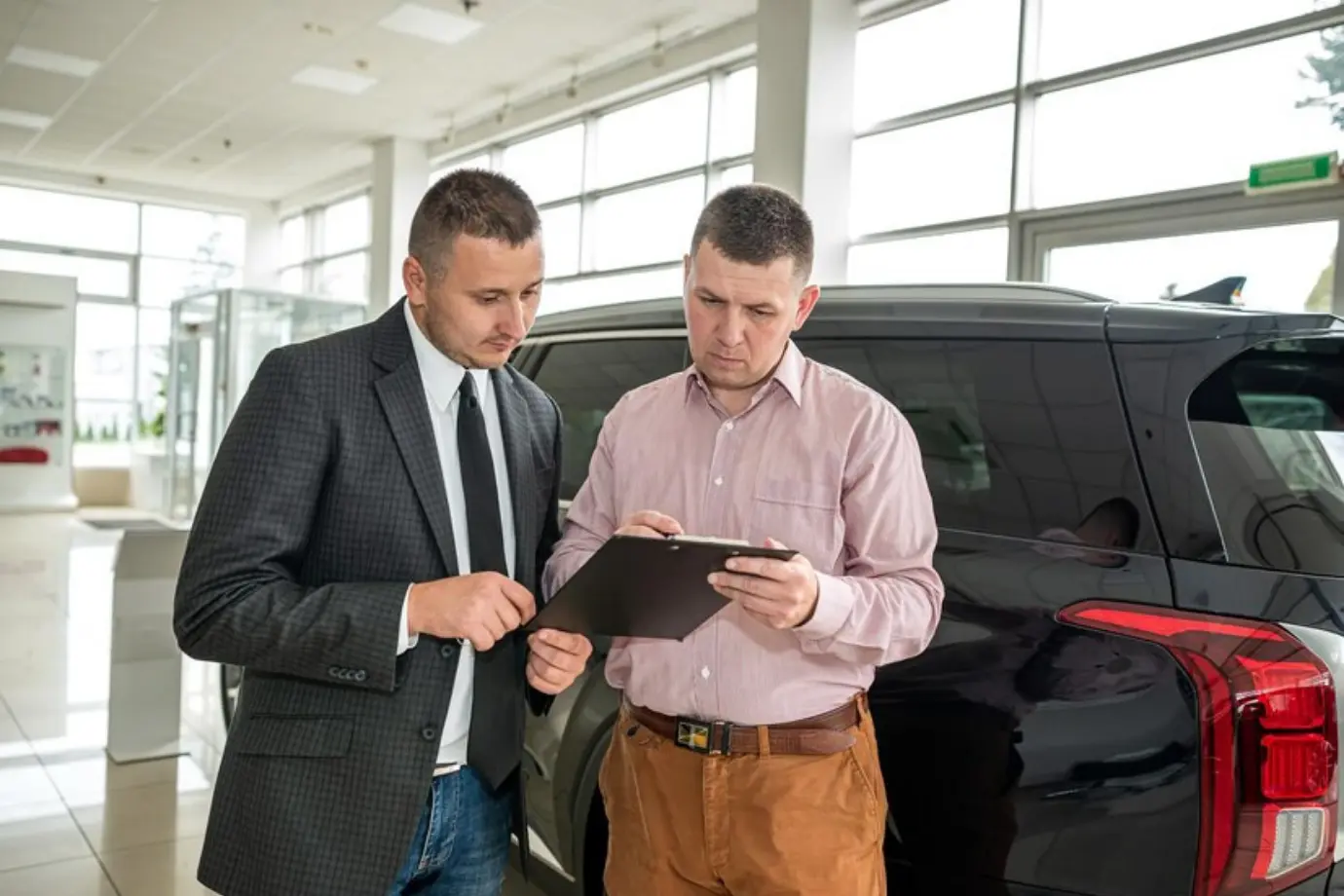Manual audit process with physical documents, checklists, and handwritten notes in a dealership setting