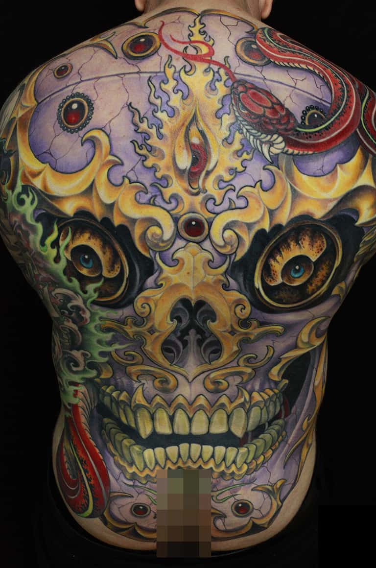 Colorful tibetan skull back tattoo with skull and rose design