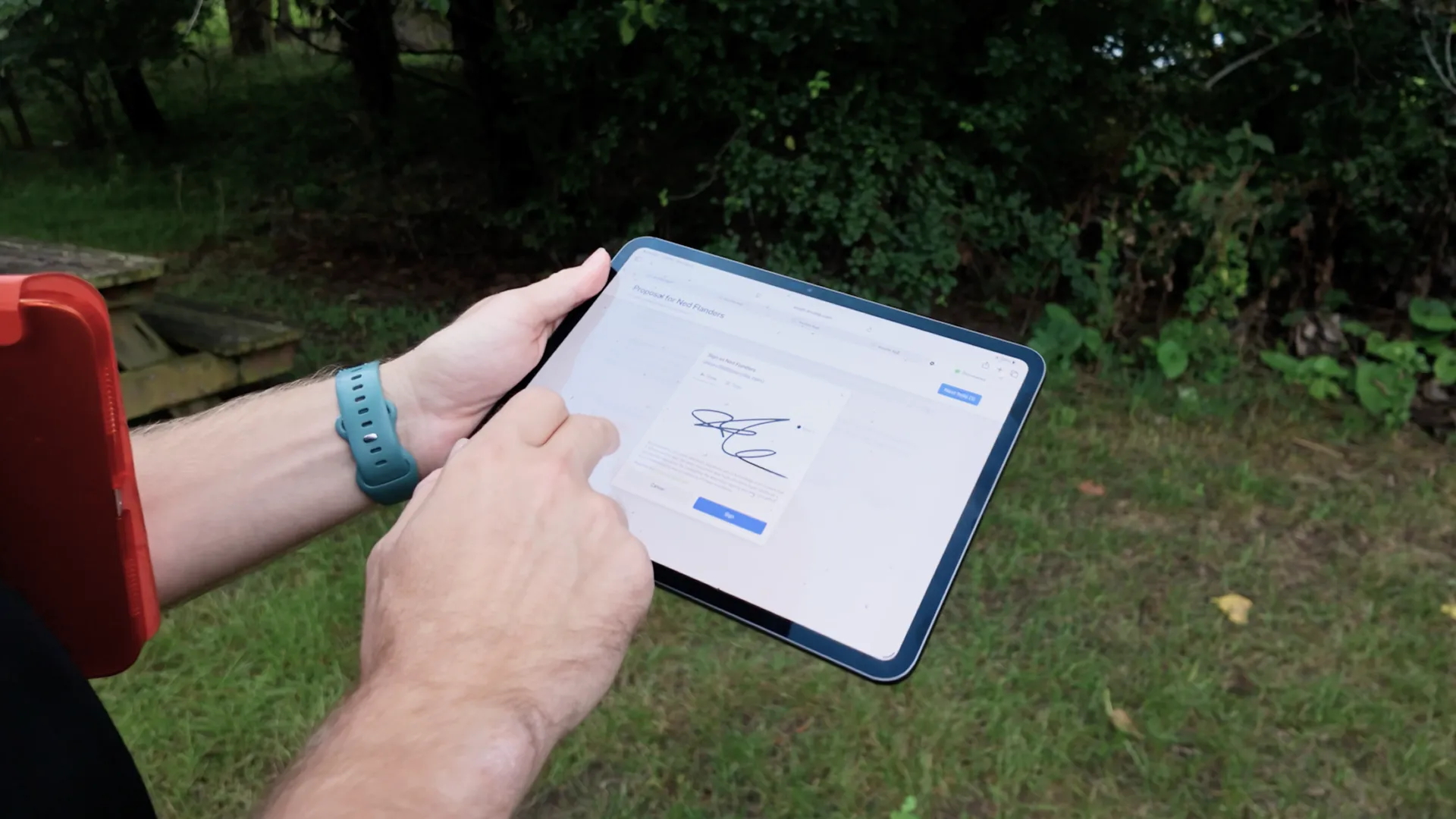 Person holding a tablet outdoors with one hand and using the other hand to interact with an electronic signature screen on the tablet.