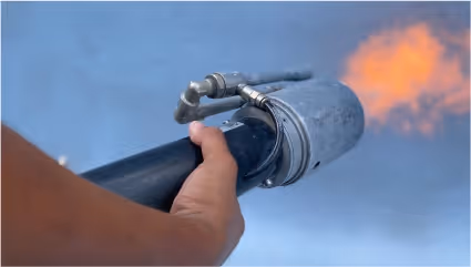 Close-up of a hand expertly applying a flamed finish to a surface using a specialized tool.