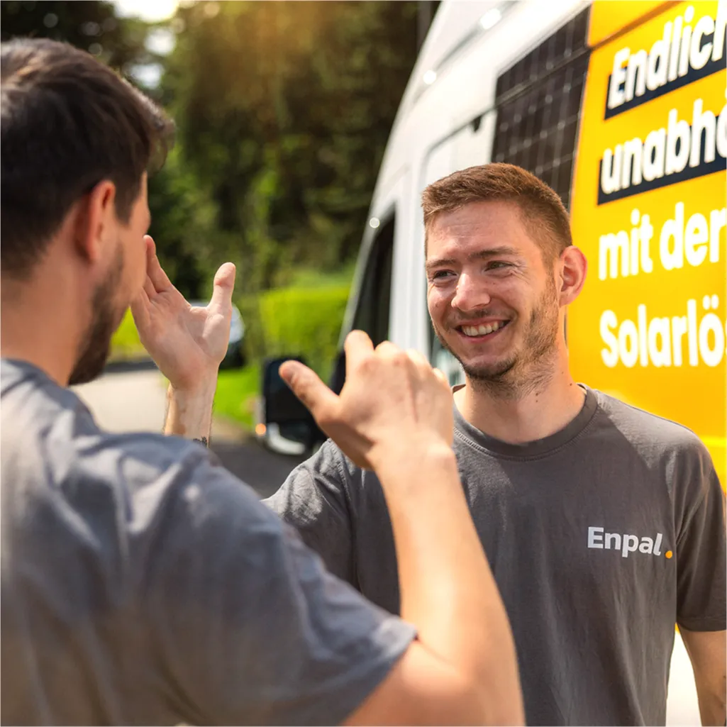 Zwei Enpal Handwerker geben sich die Hand und ein Enpal Transporter steht im Hintergrund