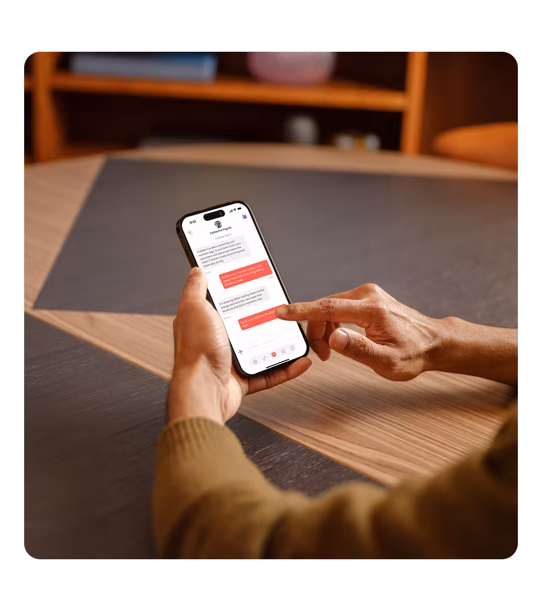 Person holding a smartphone in one hand and using the other hand to scroll through a messaging app with red and white chat bubbles.