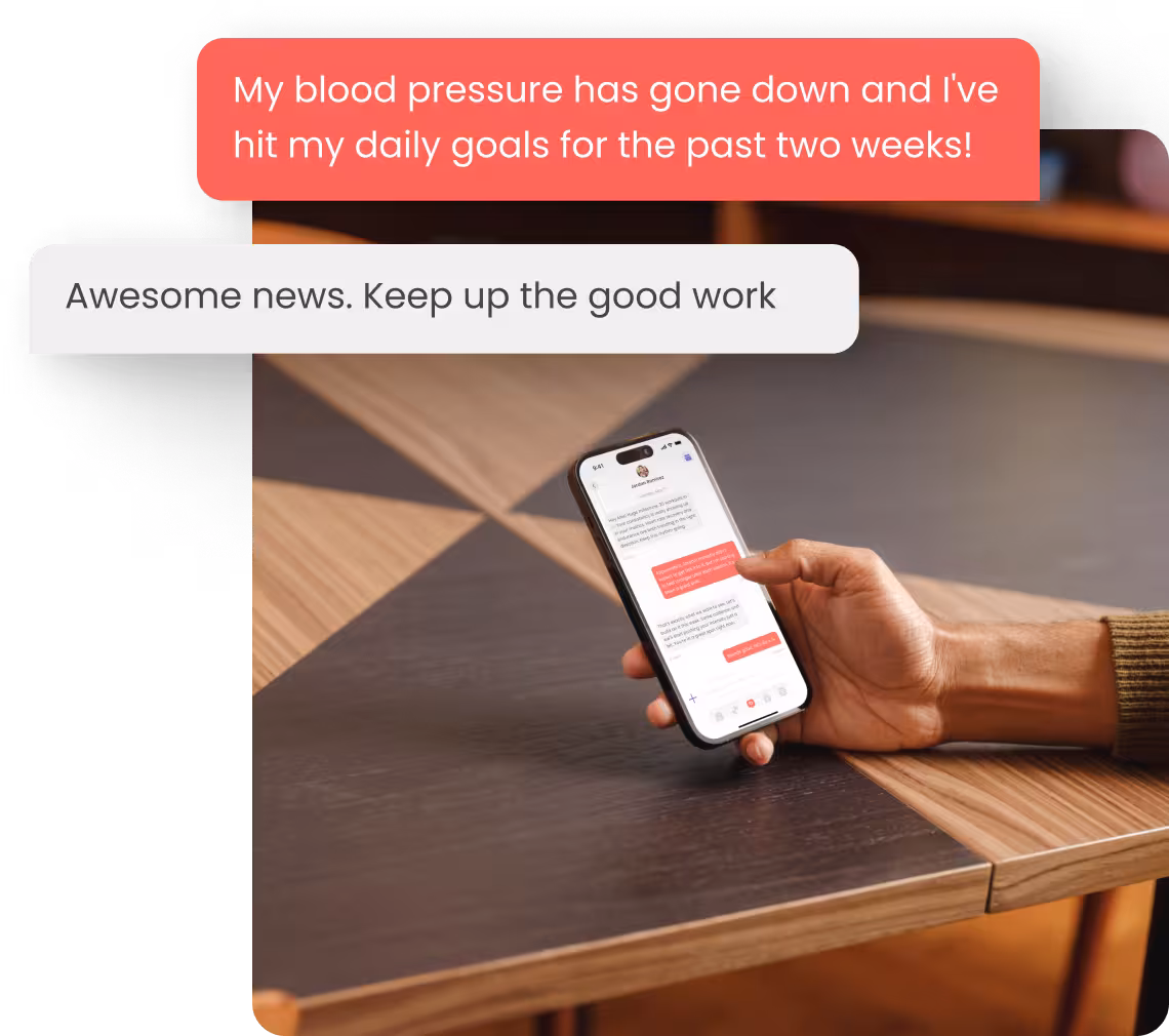Hand holding a smartphone showing a text conversation about blood pressure improvement and encouragement.