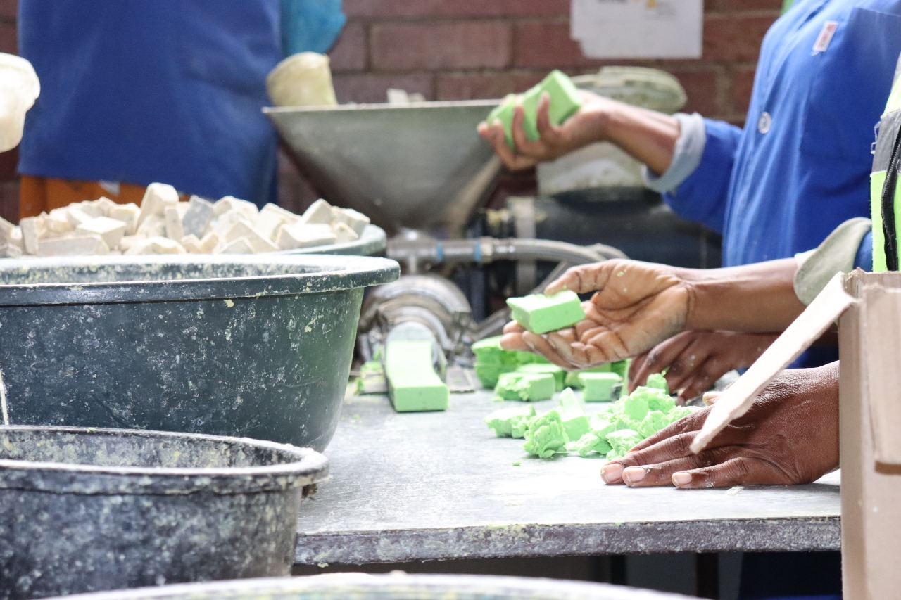 Hands pressing fresh green recycled soap bars at a hub