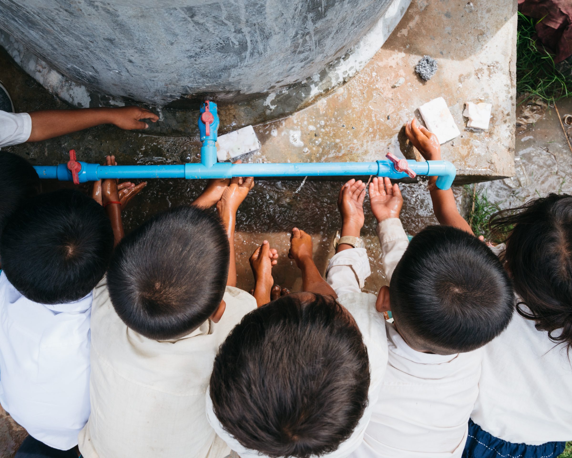 Children washing hands at a blue pipe water point at a school